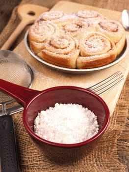 Homemade cinnamon snails with kitchen utensils on a rustic wooden kitchen table
