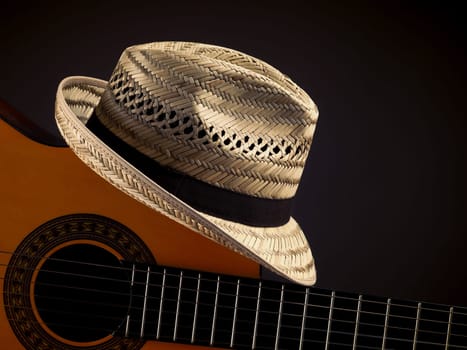 Summer straw hat with an acoustic guitar on a dark background