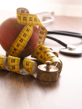 Healthy food concept with an organic apple and a stethoscope on a wooden table