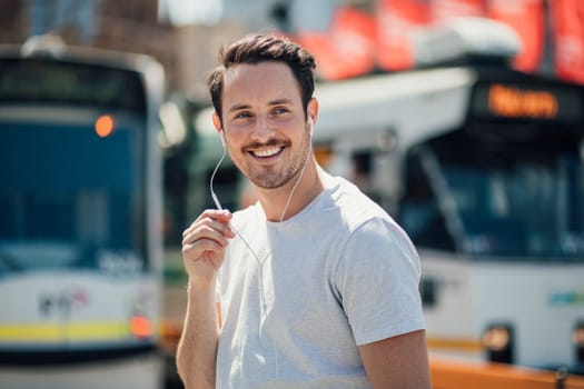 Millennial man is walking through Melbourne city, using his earphones to have a phonecall with someone.