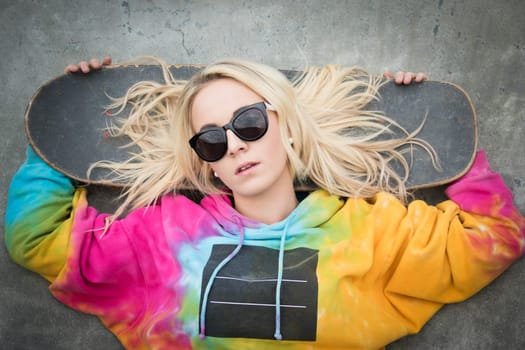 Blond skater girl laying down with board