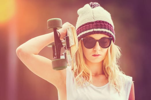 Pretty blond teen girl holding skateboard