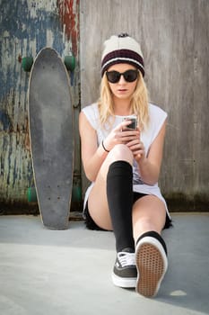 Pretty blond skater girl text messaging listening to music