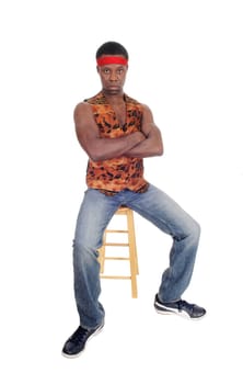 A tall and handsome African American man sitting on a bar chair.in jeans and vest with red headband, isolated for white background.