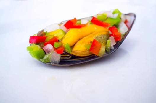 Saltwater mussel shell seasoned with raw chopped vegetables or Mussel vinaigrette. Closeup