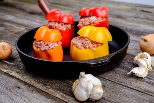 colorful filled pepper,garlic and onion in iron pan on wooden ground