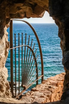 Closeup of protective railings on ocean wall viewed though stone window.
