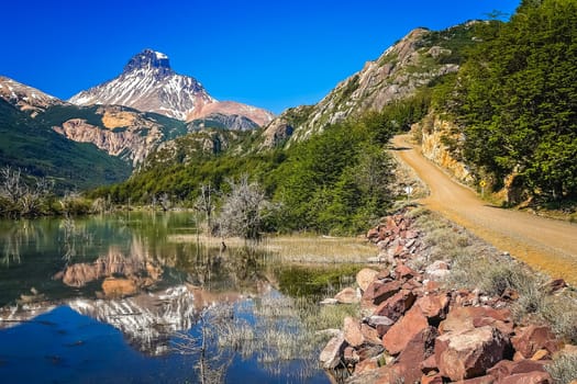 Gravel Carretera Austral road and reflection of mount Cerro Castillo, Patagonia, Chile