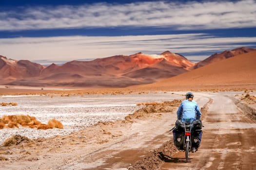 Woman cycling on the sandy road in Altiplano in Bolivia