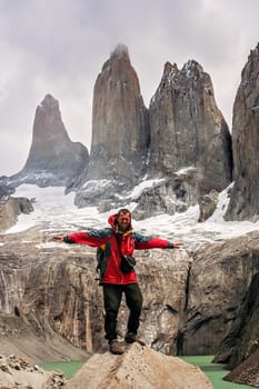 Man standing on the rock in front of the stunning Torres del Paine peaks, Patagonia, southern Chile, South America