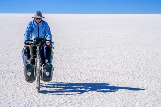 Lonely female cyclist travelling solo through the Salar de Uyuni in Bolivia, the biggest salar in the world