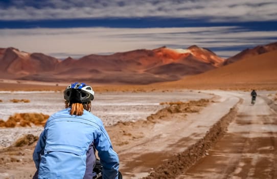 Woman cycling on the sandy road in Altiplano in Bolivia