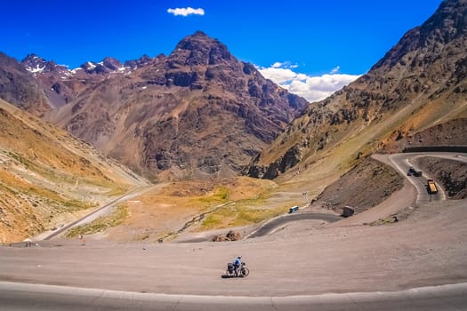 Female cyclist riding downhill on the twisting and turning switchbacks on the beautiful road through high Andes from Artgentina to Chile, South America