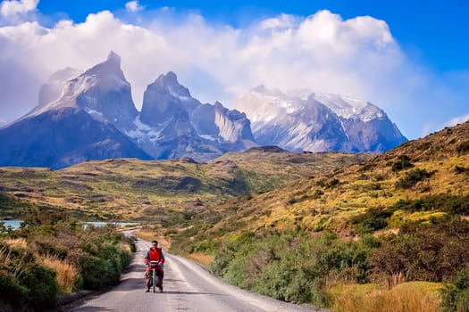 Man on a bicycle on the road leading to the impressive Cuernos del Paine peaks in Torres del Paine National Park, Chile, South America
