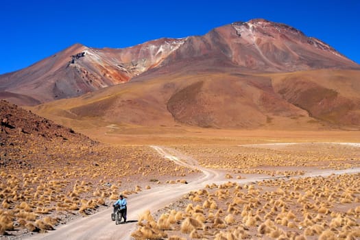Woman cycling on the sandy road in Altiplano in Bolivia
