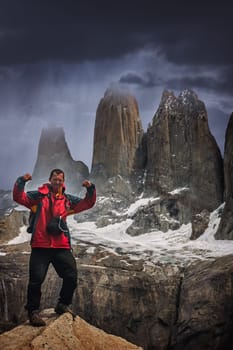 Man standing on the rock in front of the stunning Torres del Paine peaks, Patagonia, southern Chile, South America
