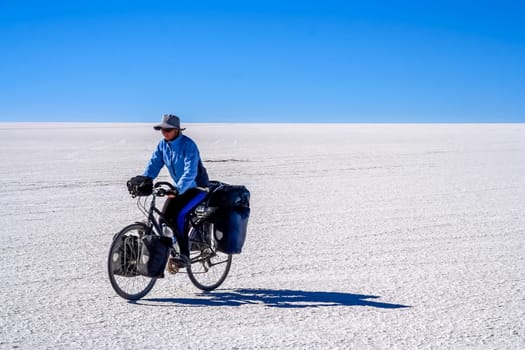 Lonely female cyclist travelling solo through the Salar de Uyuni in Bolivia, the biggest salar in the world