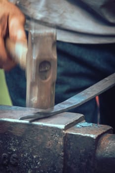 A blacksmith hammering hot iron during medieval fair festival in Streatham Park in London