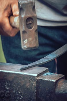 A blacksmith hammering hot iron during medieval fair festival in Streatham Park in London
