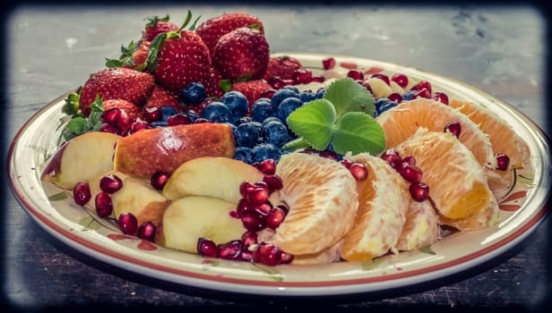 A closeup view of a platter of mixed fruits including strawberries, oranges, blueberries, apples and bananas