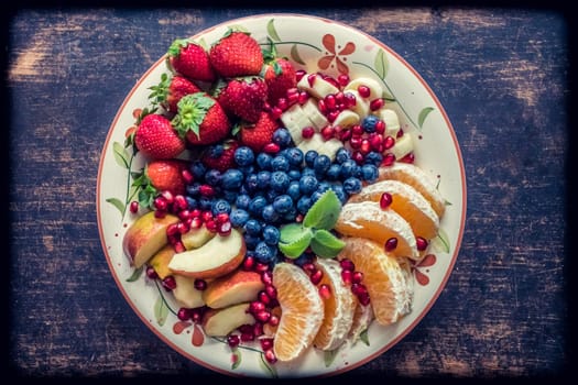 A closeup view of a platter of mixed fruits including strawberries, oranges, blueberries, apples and bananas