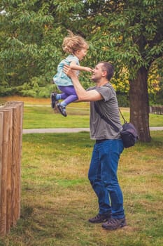 Father catching her daughter jumping from high wooden poles
