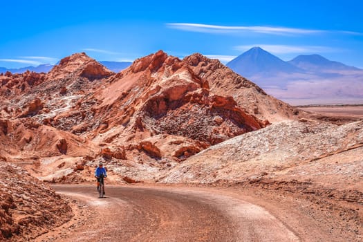Female cyclist traveling on the road through the famous Valle the la Luna near San Pedro de Atacama, Chile, South America