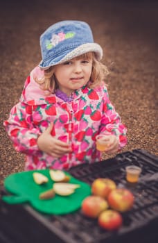 Portrait of a cute little girl tasting fresh organic apple juice at a local farmers market