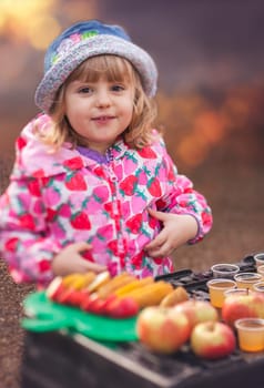 Portrait of a cute little girl tasting fresh organic apple juice at a local farmers market