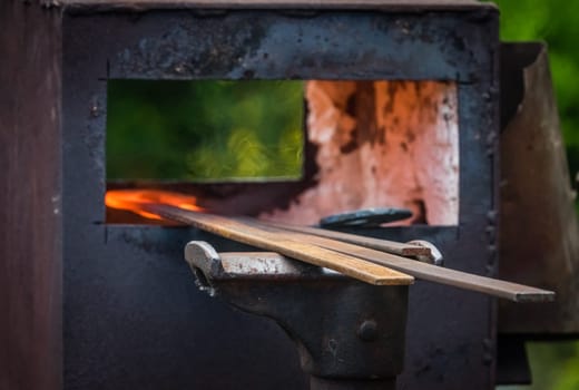 A blacksmith inserting steel rods into the hot oven  during medieval fair festival in Streatham Park in London