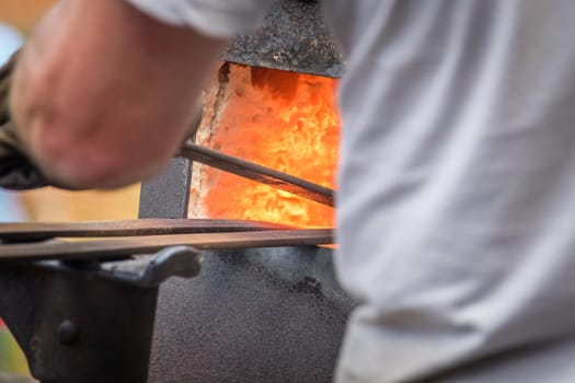 A blacksmith inserting steel rods into the hot oven  during medieval fair festival in Streatham Park in London