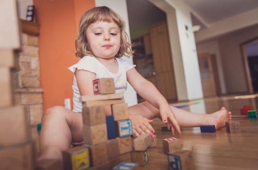 Girl playing with building blocks on floor at home