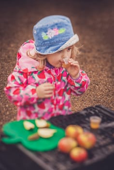 Portrait of a cute little girl tasting fresh organic apple juice at a local farmers market