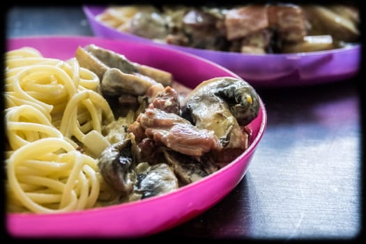 Portion of spaghetti carbonara pasta served on a childrens pink plate at home