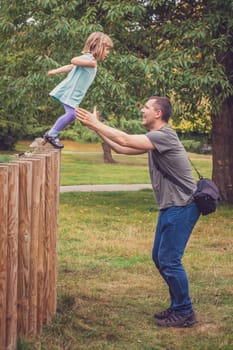 Father catching her daughter jumping from high wooden poles