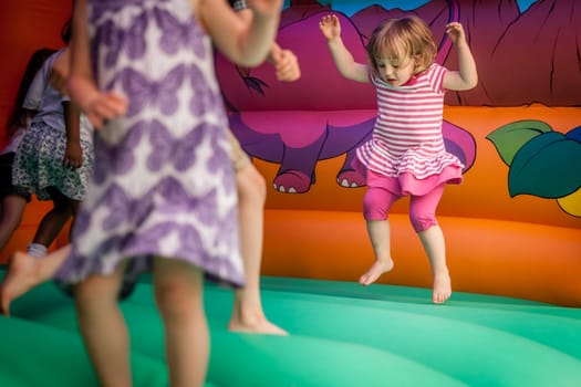 Cute little girl jumping inside the inflatable bouncy castle