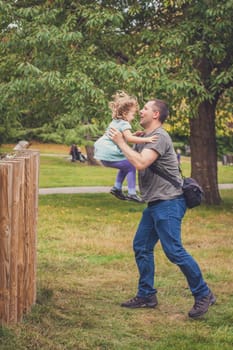 Father catching her daughter jumping from high wooden poles
