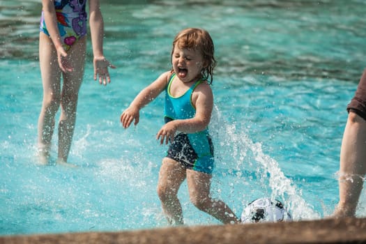 Cute little girl having fun in the kids pool in the summer