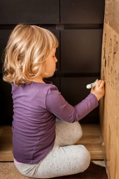 Little girl drawing on a cardboard at home