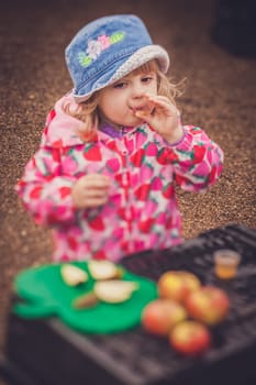Portrait of a cute little girl tasting fresh organic apple juice at a local farmers market