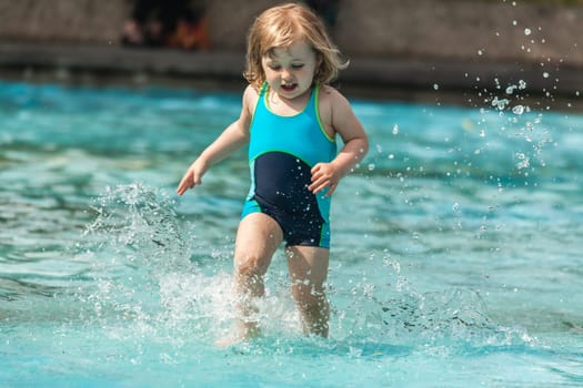 Cute little girl having fun in the kids pool in the summer