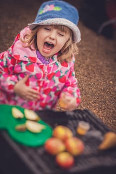 Portrait of a cute little girl tasting fresh organic apple juice at a local farmers market