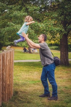 Father catching her daughter jumping from high wooden poles