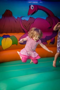 Cute little girl jumping inside the inflatable bouncy castle
