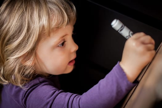 Little girl drawing on a cardboard at home