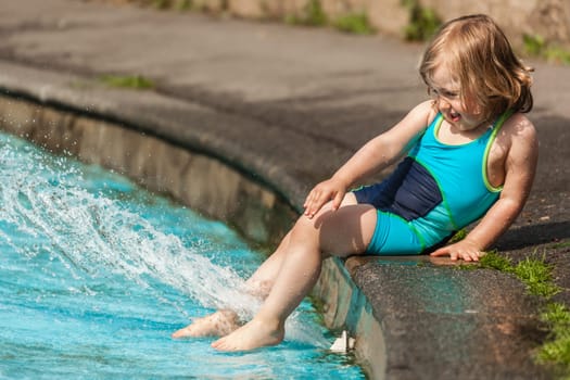 Cute little girl having fun in the kids pool in the summer