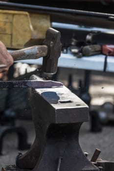 A blacksmith hammering hot iron during medieval fair festival in Streatham Park in London