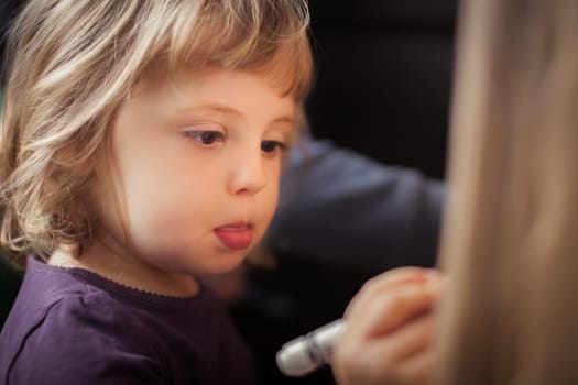 Little girl focused on drawing on a cardboard at home