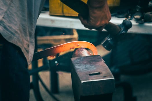 A blacksmith hammering hot iron during medieval fair festival in Streatham Park in London
