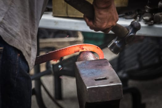 A blacksmith hammering hot iron during medieval fair festival in Streatham Park in London